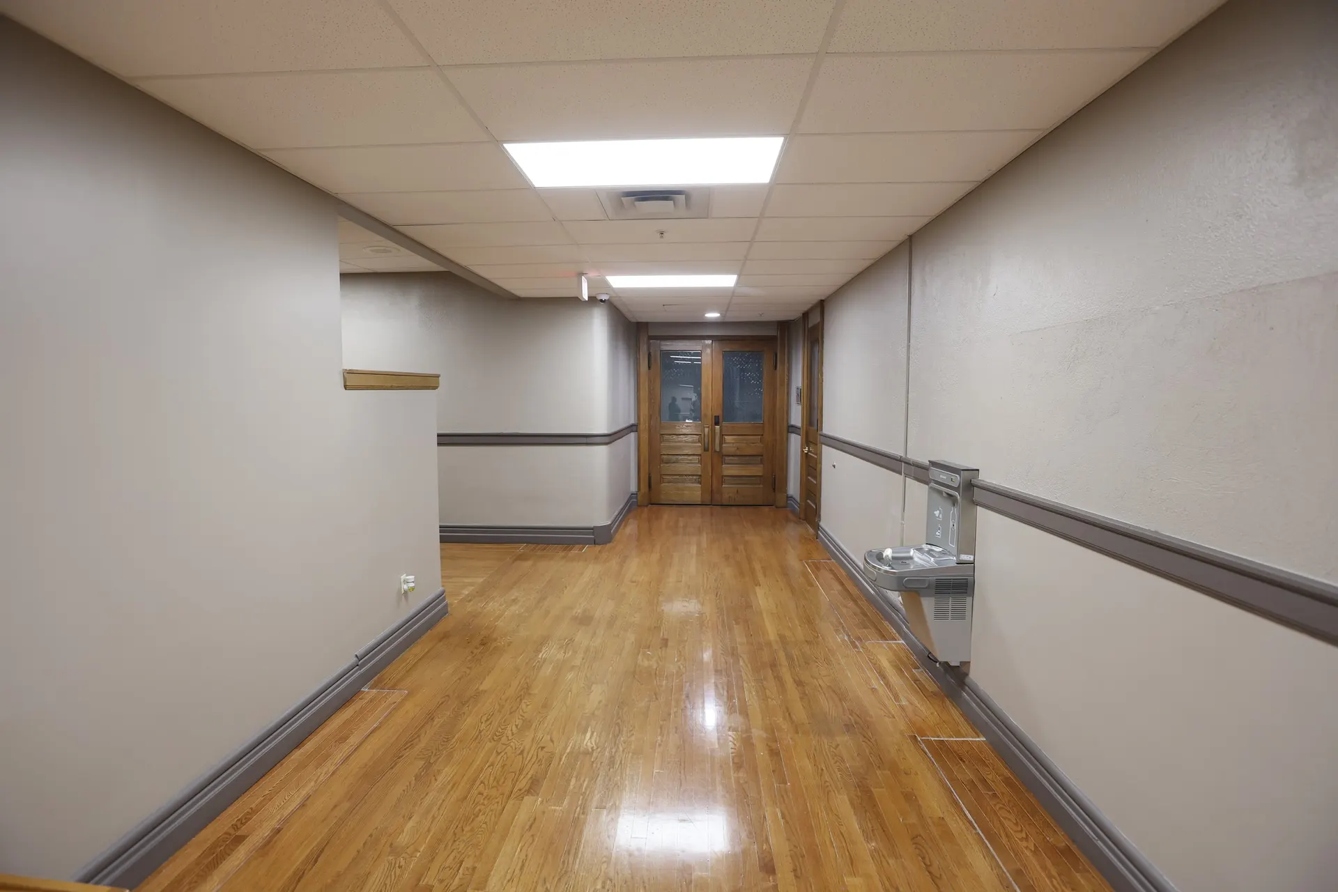 A hardwood corridor ending at the original wood double doors