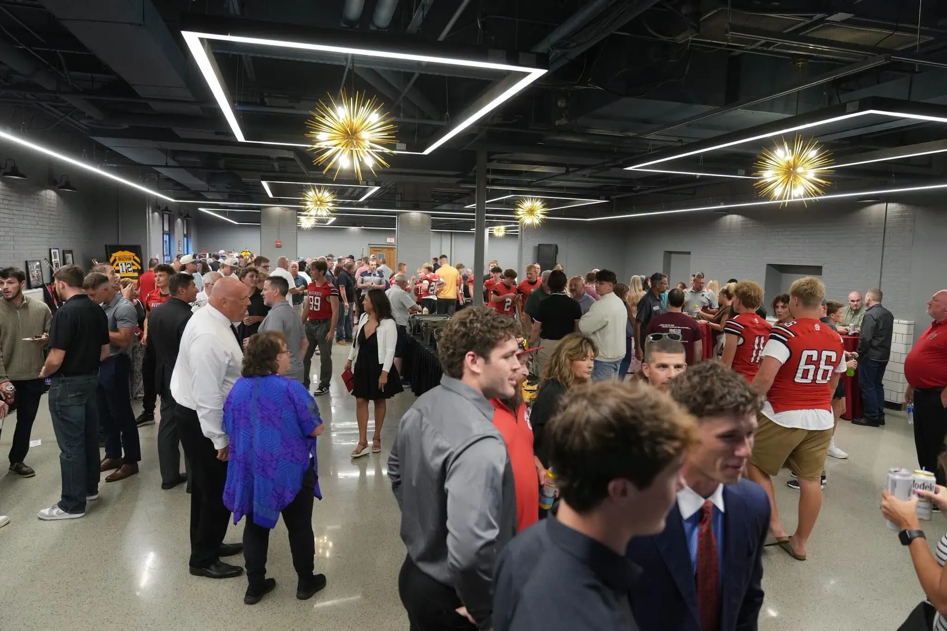 A full crowd at an event in the Event Center at Wadsworth Square, under gold starburst chandeliers and lit ceiling frames