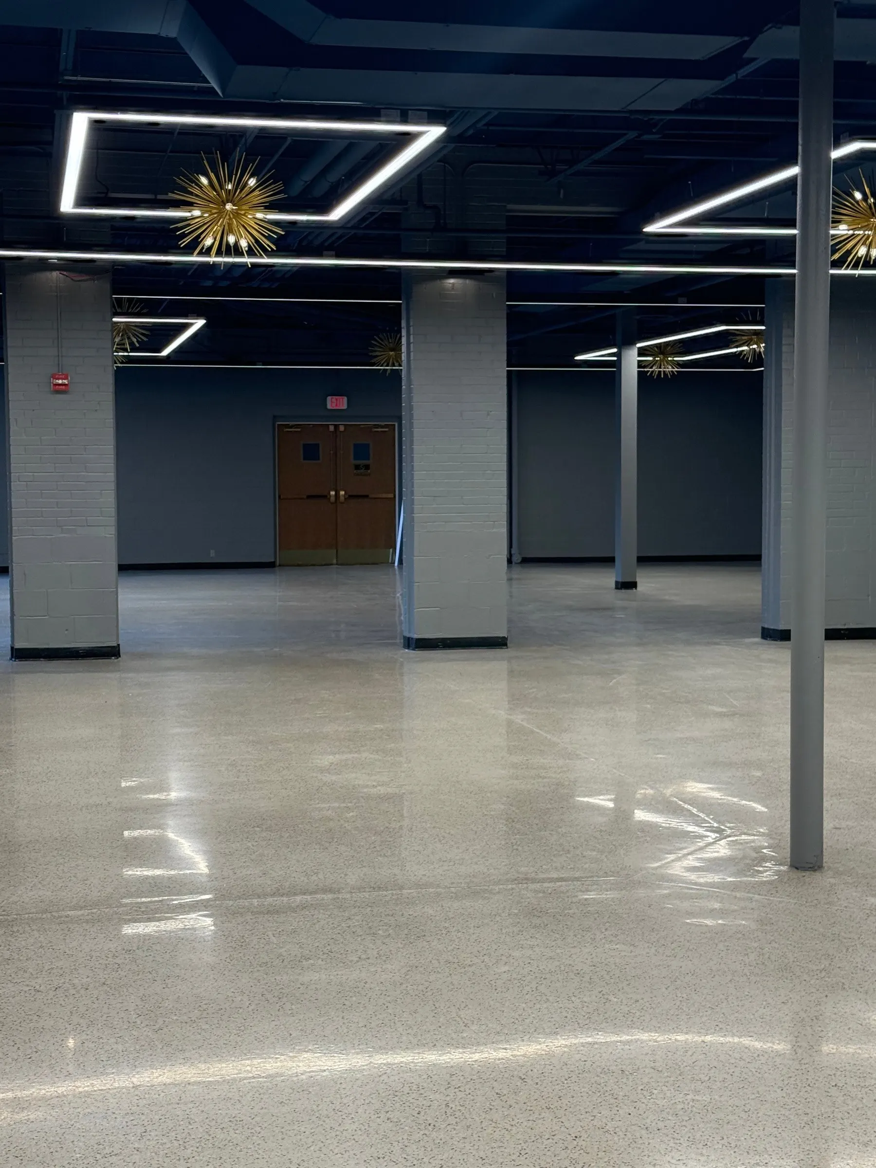 The empty event center floor, polished concrete and columns, ready to be set for an event