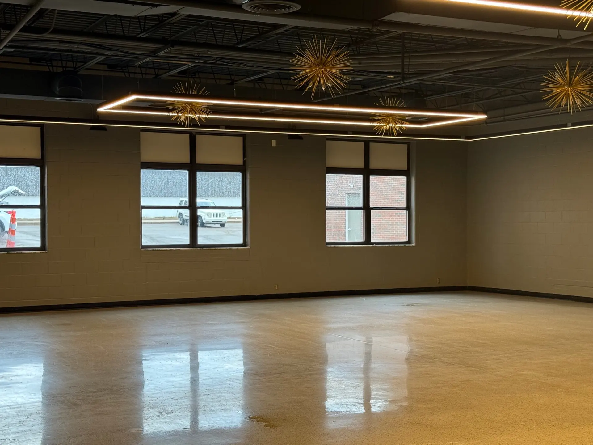 A wide view of the empty event center room, polished floor and a row of windows