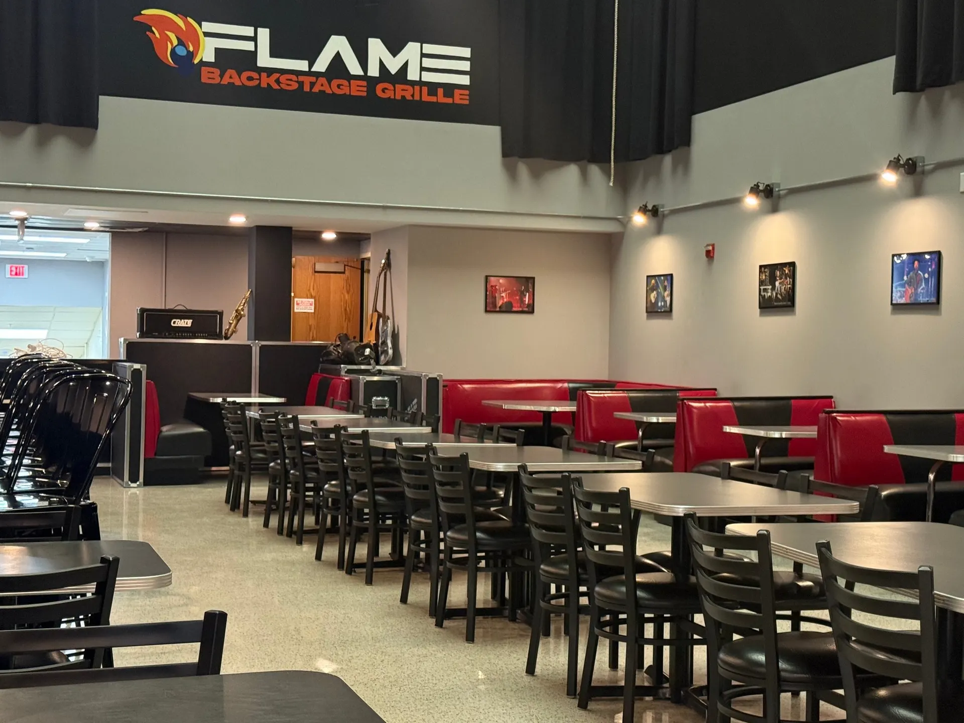 Red and black booths and tables in the Flame dining room under the stage sign