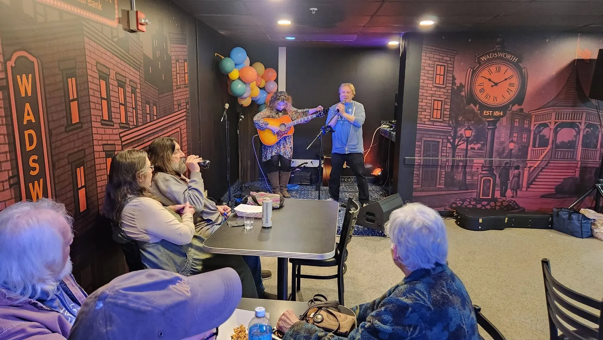 A duo playing live at Flame Backstage Grille & Bar in front of the downtown Wadsworth mural