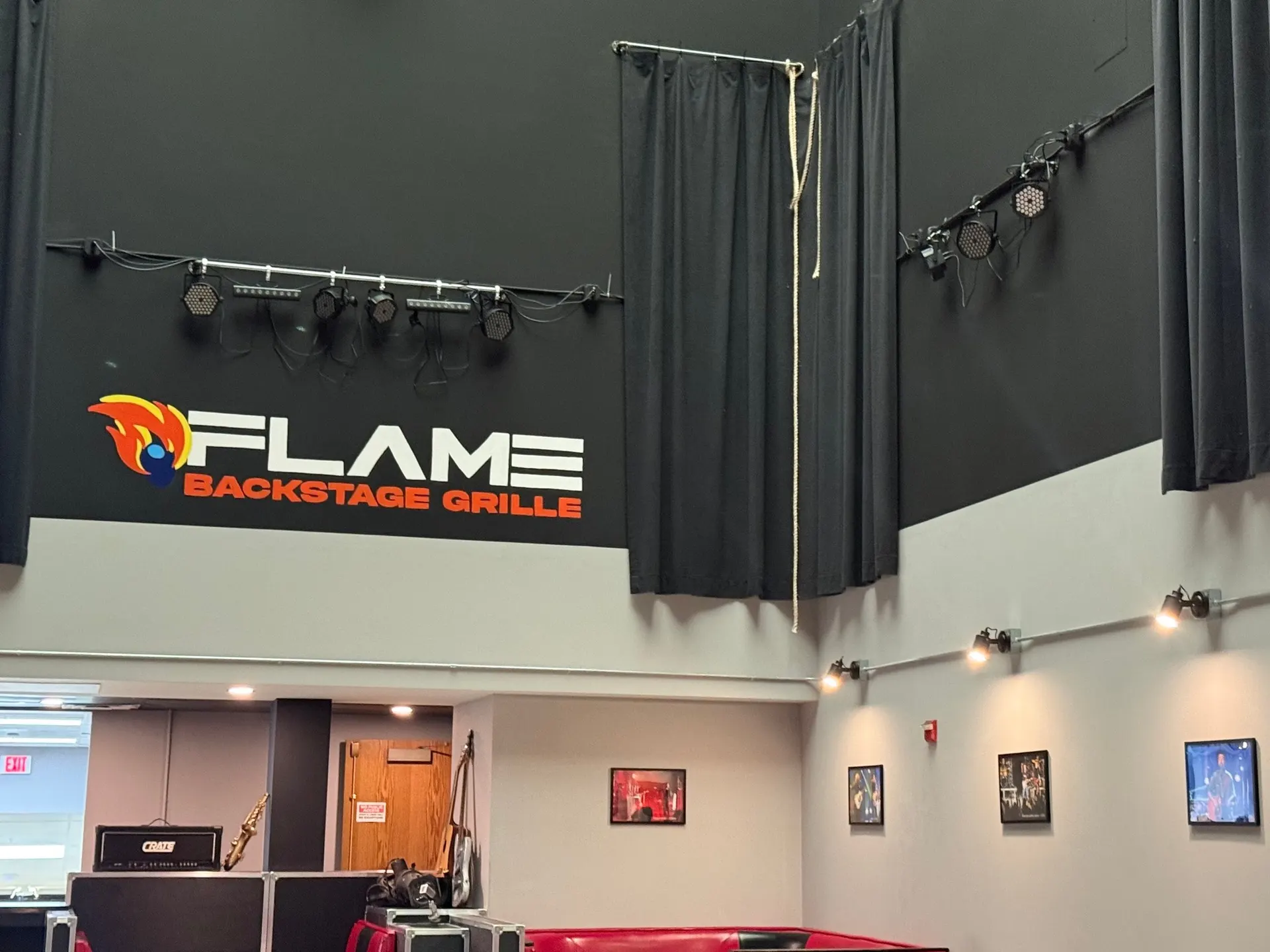 The Flame Backstage Grille sign above the small stage, with black curtains and stage lights