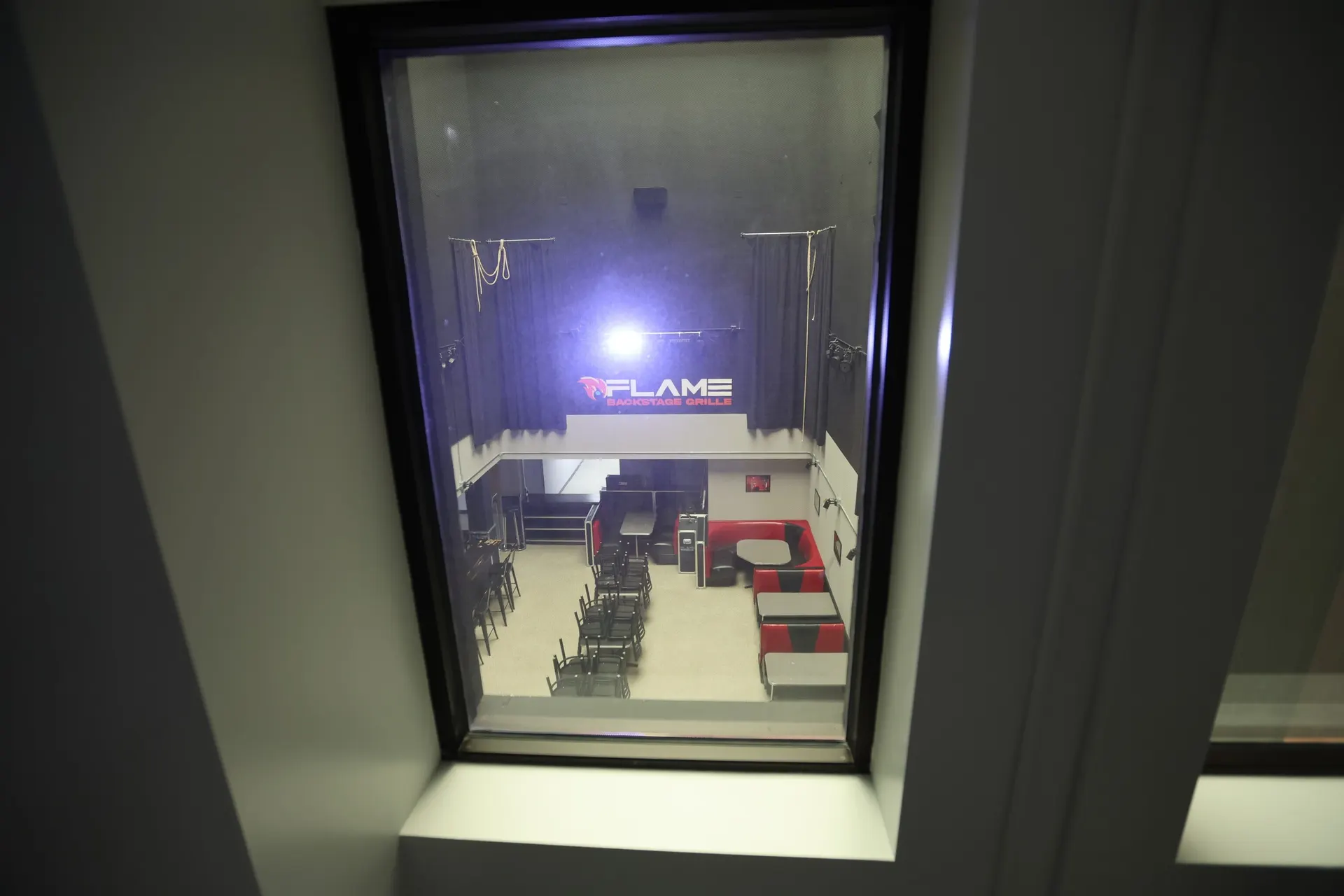 Flame Backstage Grille and Bar seen from an upstairs window, tables set and the Flame sign lit