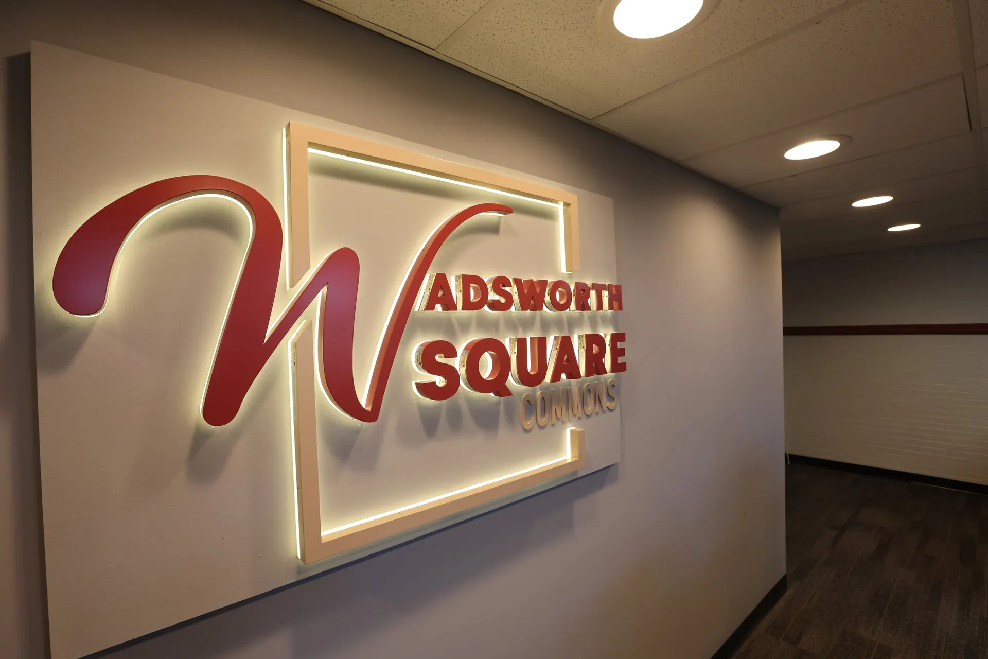 The backlit Wadsworth Square Commons sign on the lobby wall
